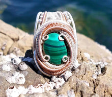 Malachite wire wrapped pendant on a top of the rock